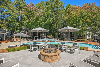 A poolside area with a fire pit in the middle.